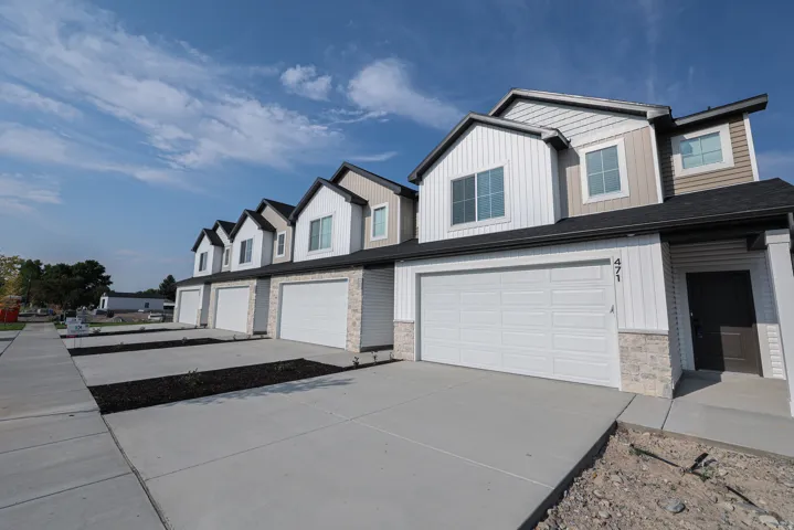 Contemporary townhome exterior featuring vertical siding, stone accents, and a two-car garage