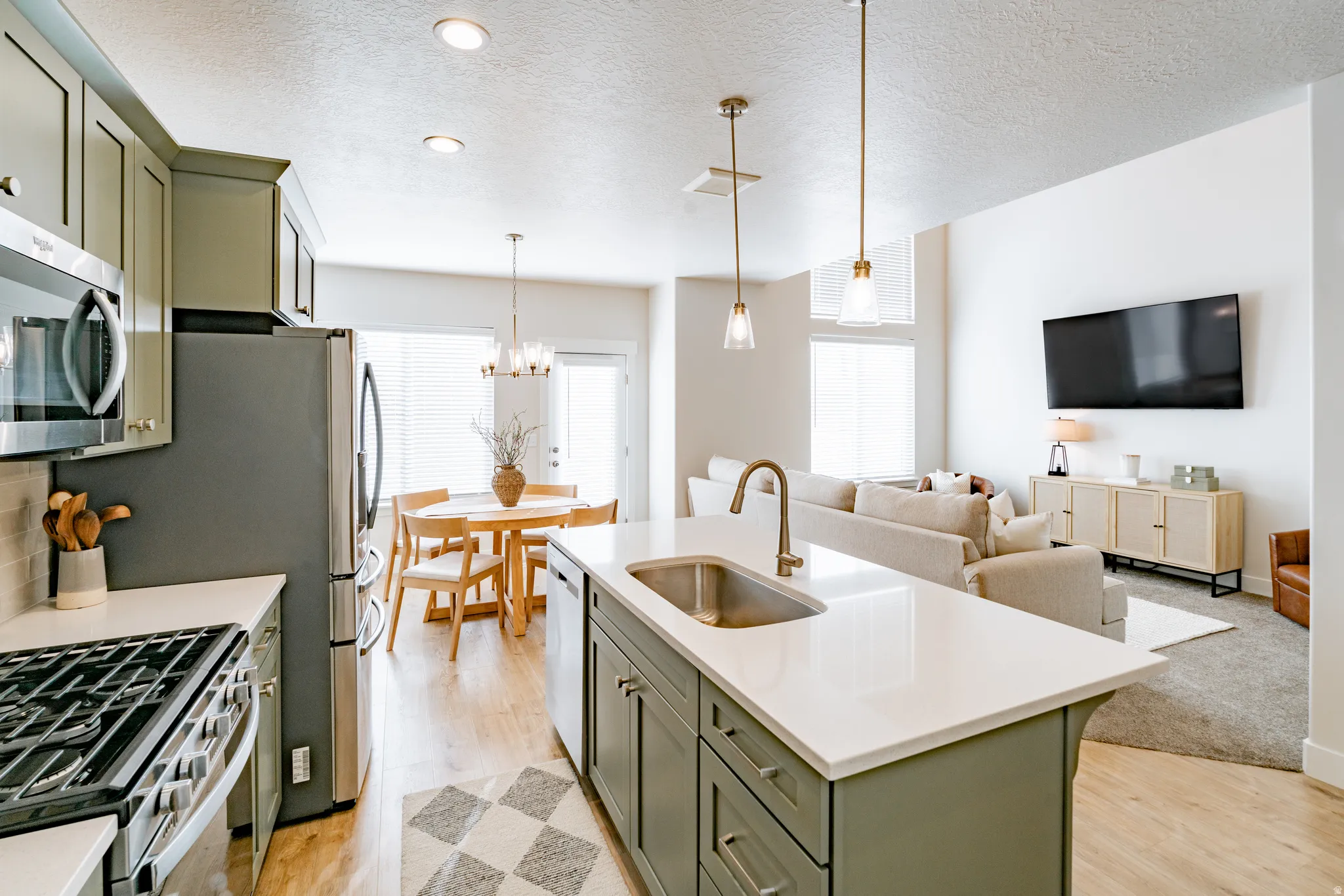 Open concept living space featuring a kitchen island with sink, stainless steel appliance