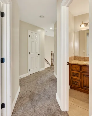 Hallway with neutral carpeting, recessed ceiling lighting, and crisp white trim