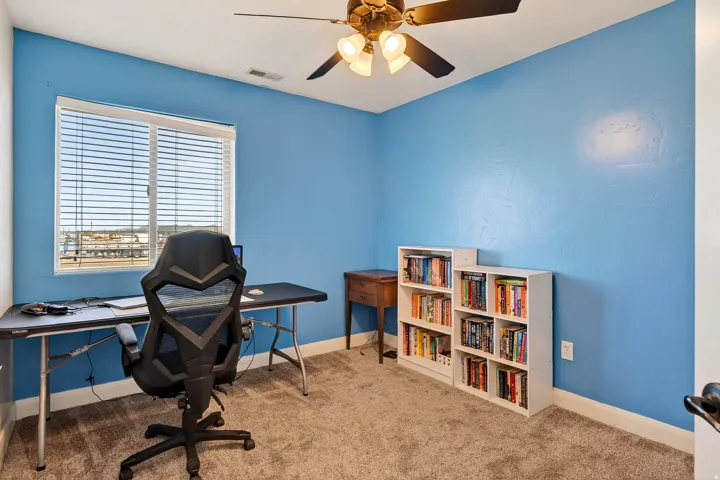 Carpeted room featuring a ceiling fan with light fixture, a window with blinds, and white baseboards