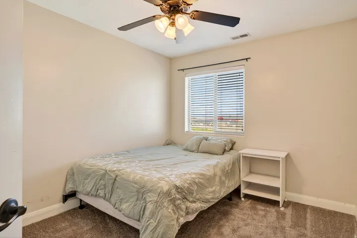 Compact room featuring light beige walls, brown carpet flooring, and a single window with horizontal blinds