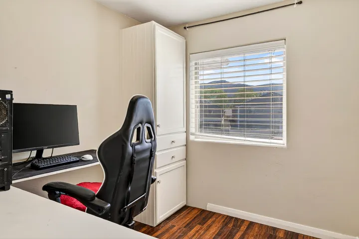 Interior space featuring wood-finish flooring, a window with horizontal blinds, and a built-in white cabinetry unit with drawers
