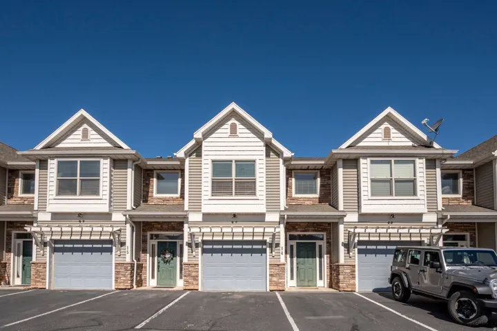 Townhome exterior featuring stone and siding finishes, individual garage access, front entry doors, and upper-level windows