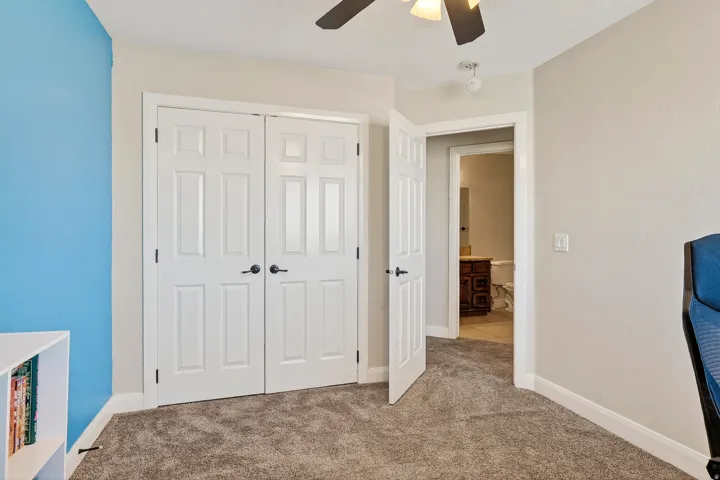 Room featuring plush carpet flooring, a ceiling fan with integrated lighting, and a closet with white bi-fold doors