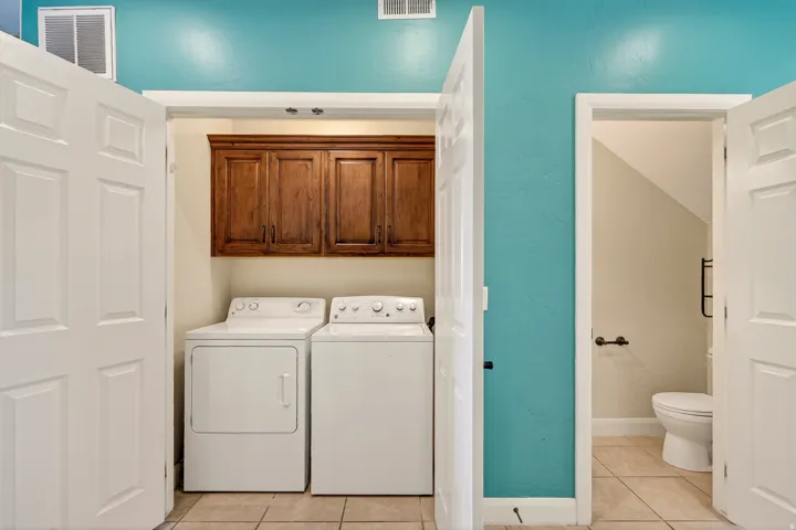Dedicated laundry area featuring wood-finish cabinetry and tiled flooring