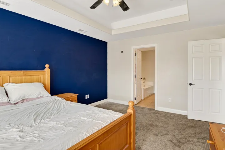 Carpeted room with a tray ceiling and a ceiling fan