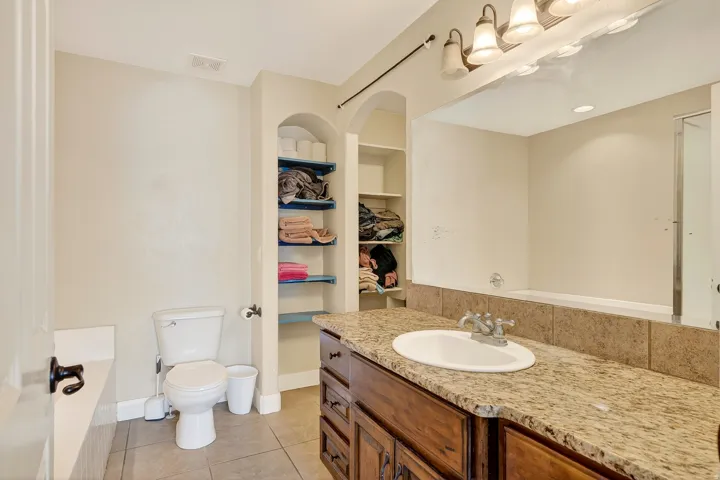 Bathroom featuring a single vanity with stone-finish countertop, undermount sink, and wood-finish cabinetry