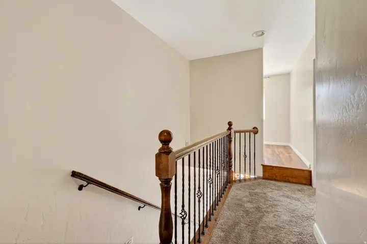 Upper landing featuring a decorative wrought iron and wood-finish railing