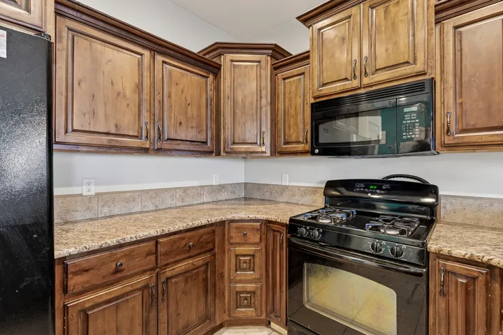 Kitchen featuring wood cabinetry, granite-style countertops, and a tiled backsplash