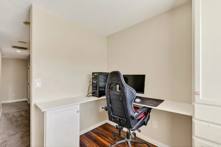 Built-in desk area featuring a light-toned countertop, wood-finish flooring, and integrated white cabinetry