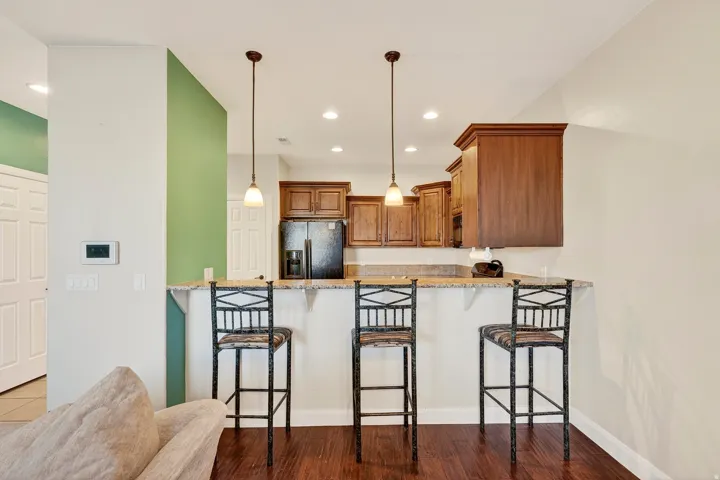 Kitchen featuring wood-finish flooring, granite countertop, rich wood cabinetry, and pendant lighting