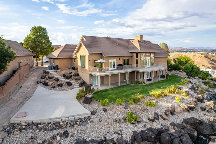 Terraced hillside property with a multi-level concrete patio, a private upper-level balcony, and a lower-level covered patio