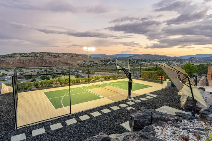 Multi-sport court with modular surfacing, perimeter fencing, and integrated basketball hoop