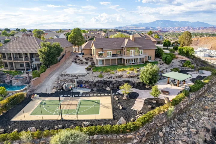 Expansive exterior featuring a full sport court, covered outdoor living area, and terraced landscaping