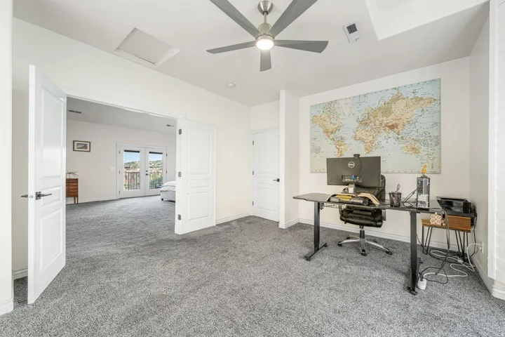 Spacious room with gray textured carpeting, a contemporary ceiling fan, and white walls