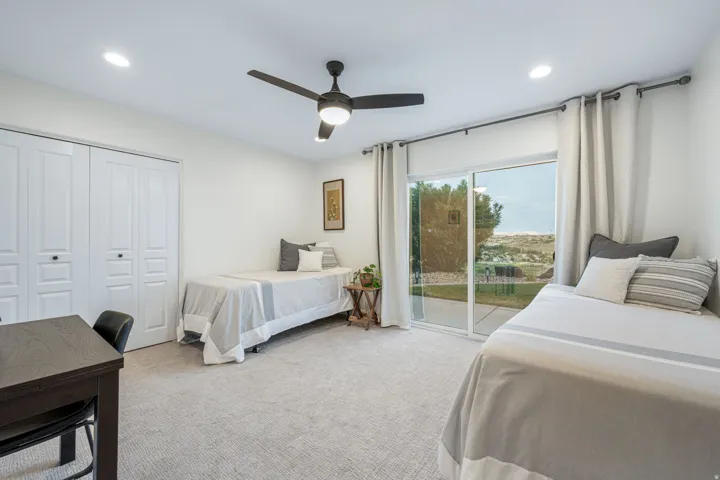 Neutral-toned room featuring a sliding glass door, white bi-fold closet doors, recessed lighting, and a ceiling fan