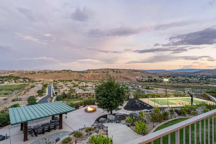 Expansive outdoor entertainment area featuring a covered patio, built-in fire pit, and multi-sport court with overhead lighting