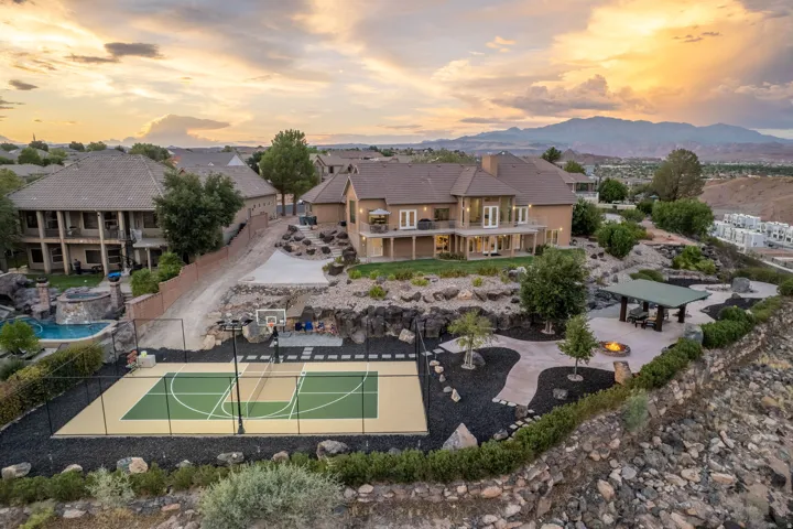 Expansive multi-level property featuring a full-size sports court, a swimming pool with a rock waterfall, a covered outdoor dining area, and a fire pit