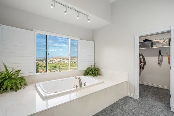 Built-in jetted tub with polished chrome fixtures and an expansive window with white plantation shutters