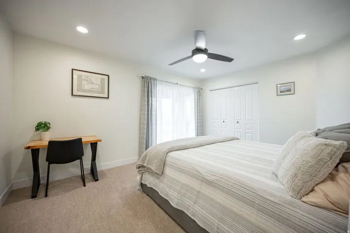 Bedroom featuring recessed lighting, a ceiling fan, light-colored carpet, white baseboards, and a bi-fold closet with panel detailing