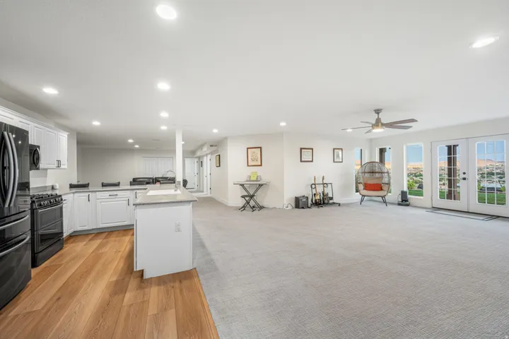 Open-concept living space featuring a modern kitchen with black appliances, white cabinetry, and a peninsula with countertop seating