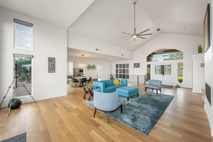 Spacious living area featuring high vaulted ceilings, light wood-finish flooring, and a modern ceiling fan