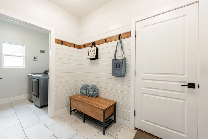 Entry area featuring shiplap wall paneling, a wood-finish coat rack, and a built-in wood-finish bench