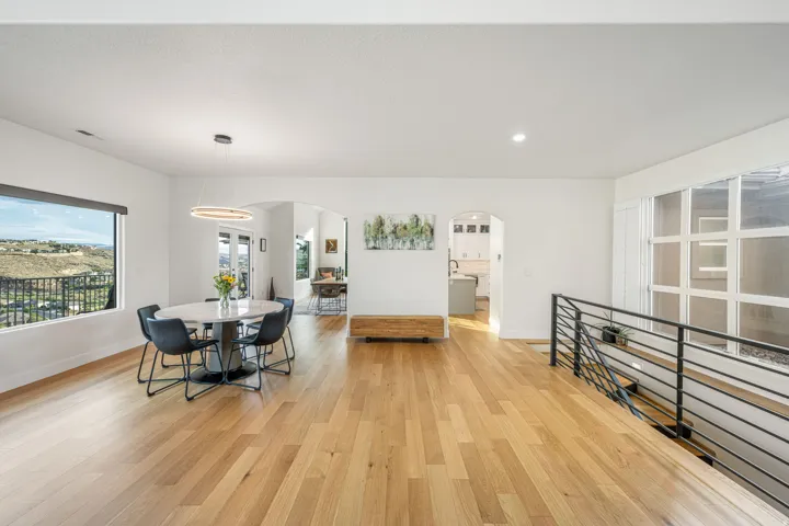 Hardwood flooring spanning a spacious open-concept area with white walls and recessed lighting