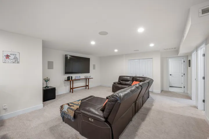 Spacious room featuring neutral carpeting, recessed lighting, and integrated wall speakers
