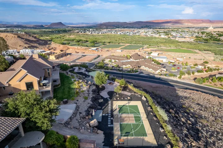 Terraced property featuring an outdoor sports court, multiple patios, and a manicured lawn