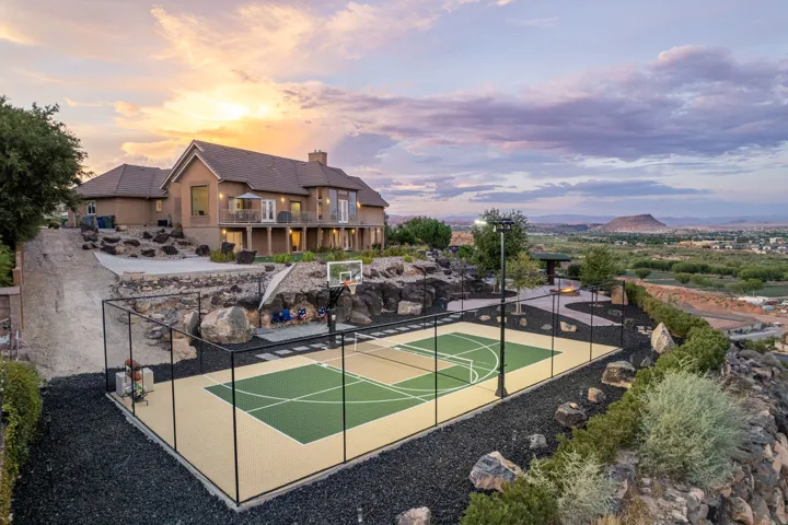 Expansive outdoor court with perimeter fencing, integrated lighting, and a basketball hoop