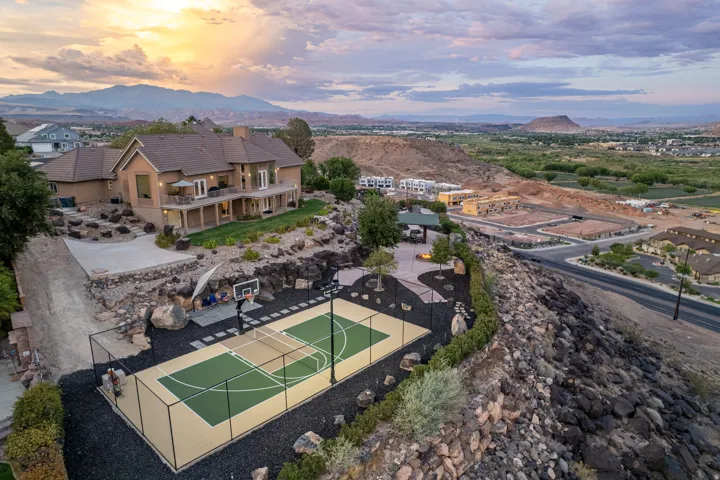 Expansive outdoor sport court with fencing, a basketball hoop, and painted court lines
