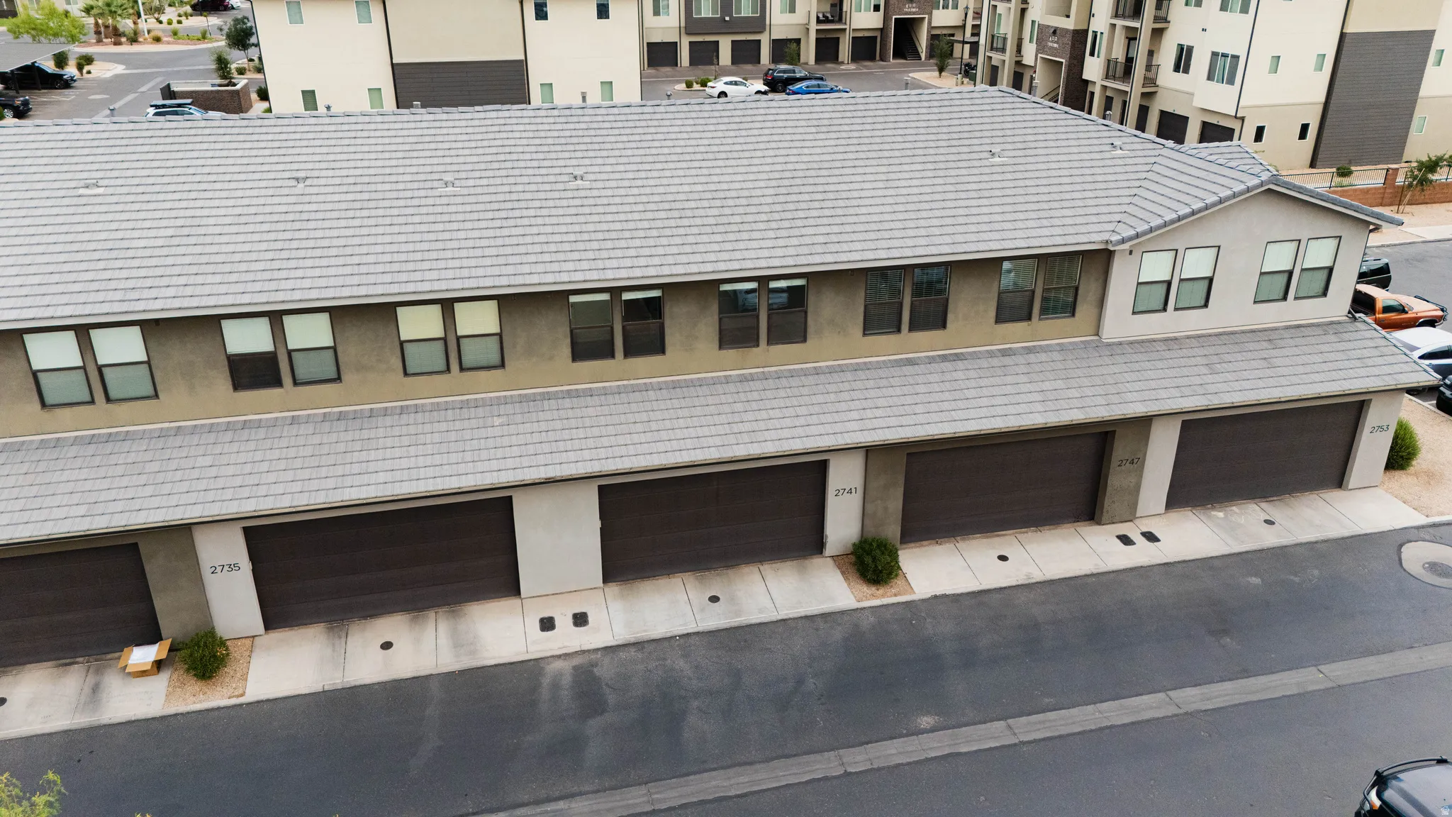 Multi-unit building featuring individual garage access and a tiled roof