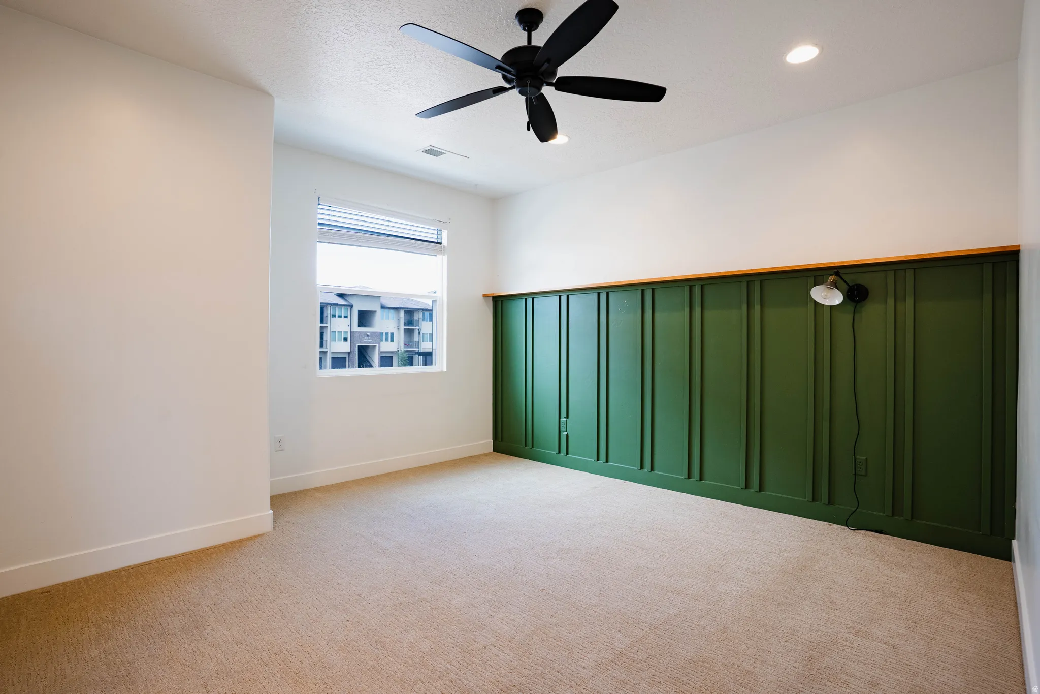 Accent wall with board and batten paneling and natural wood trim, recessed lighting, ceiling fan, and carpeted flooring