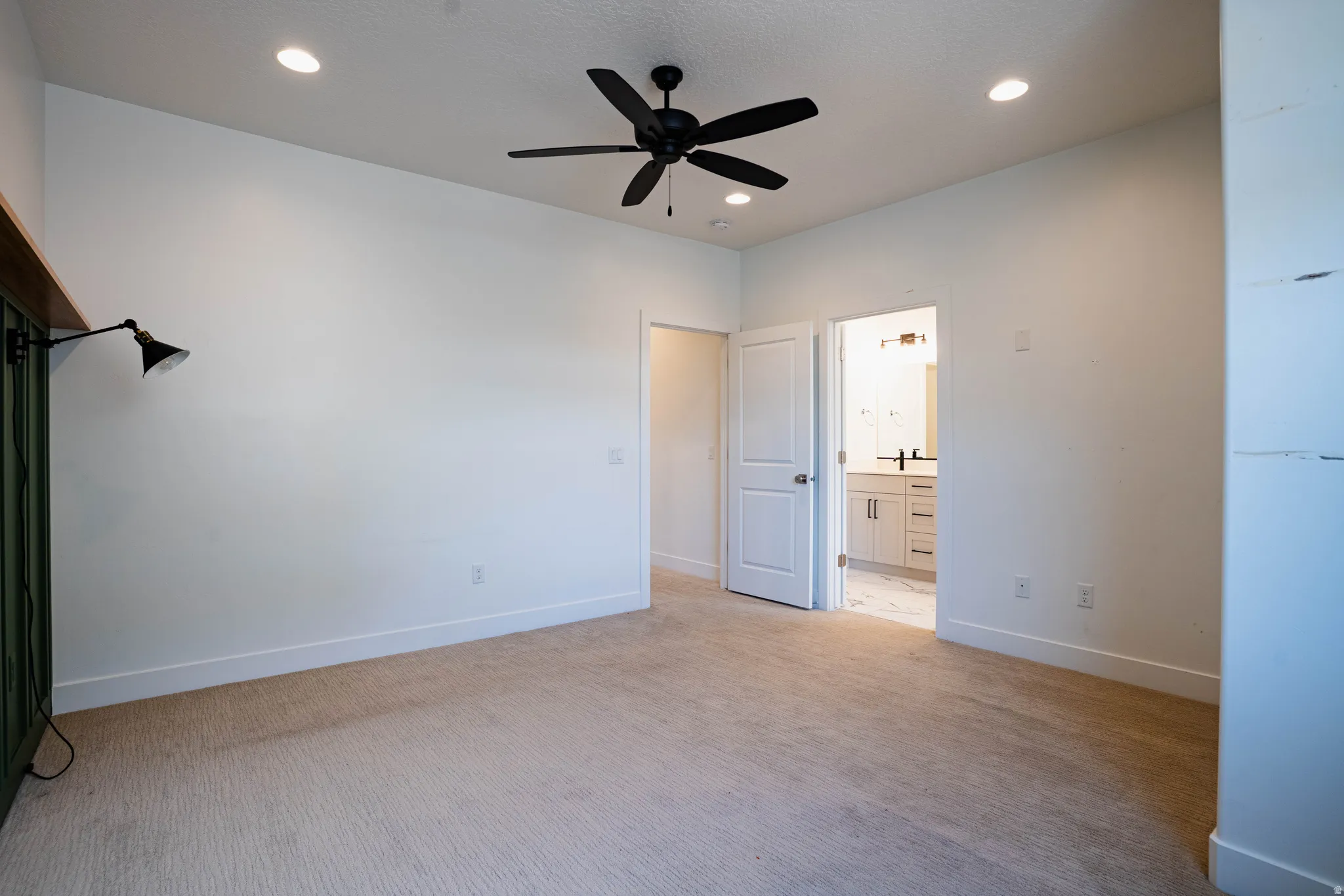 Spacious room featuring neutral carpeting, a contemporary black ceiling fan, and recessed lighting