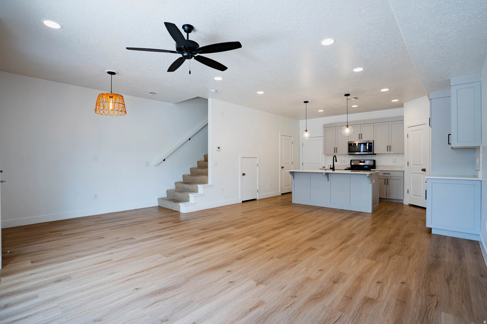 Open-concept living space featuring wood-finish flooring, recessed lighting, and a modern kitchen
