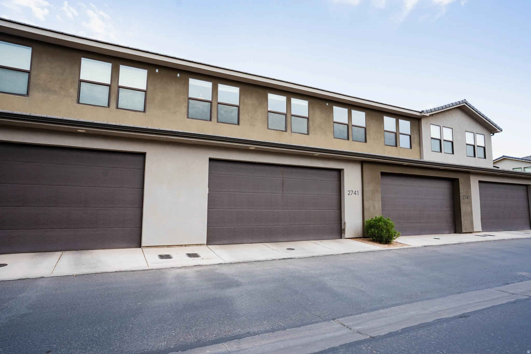 Multi-unit residential property with stucco exterior, multiple garage doors, and upper-level windows