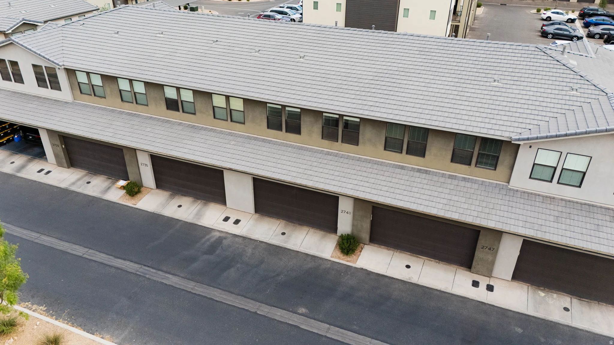 Multi-level residential building featuring individual garage access and a tiled roof