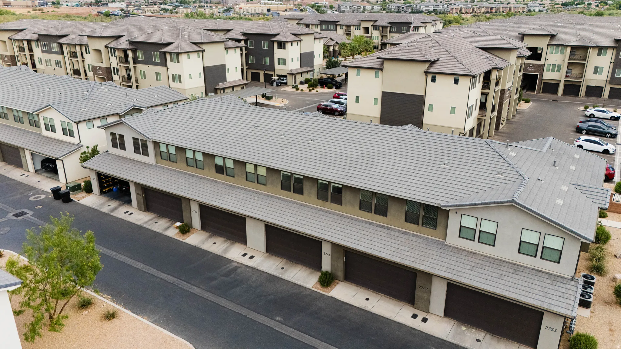 Multifamily residential building featuring a tile roof and attached garages with dark panel doors