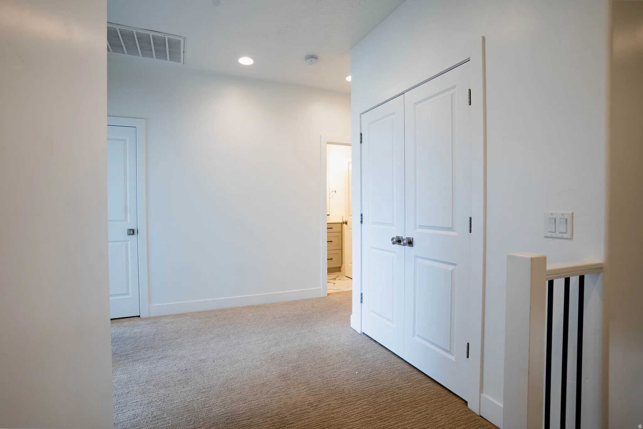 Carpeted hallway with white walls and trim