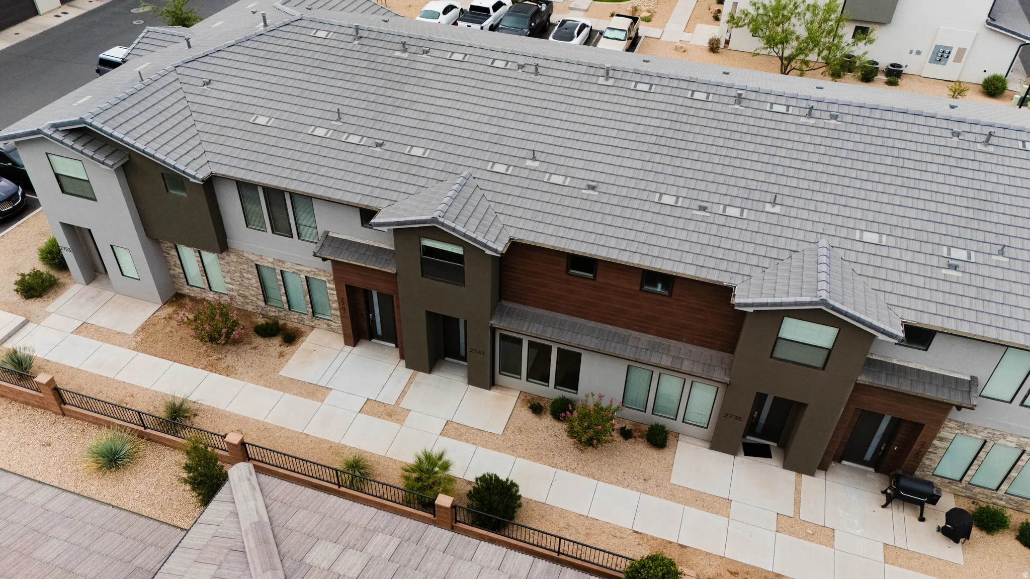Modern townhome architecture featuring a grey tile roof, stone accents, and wood-finish siding