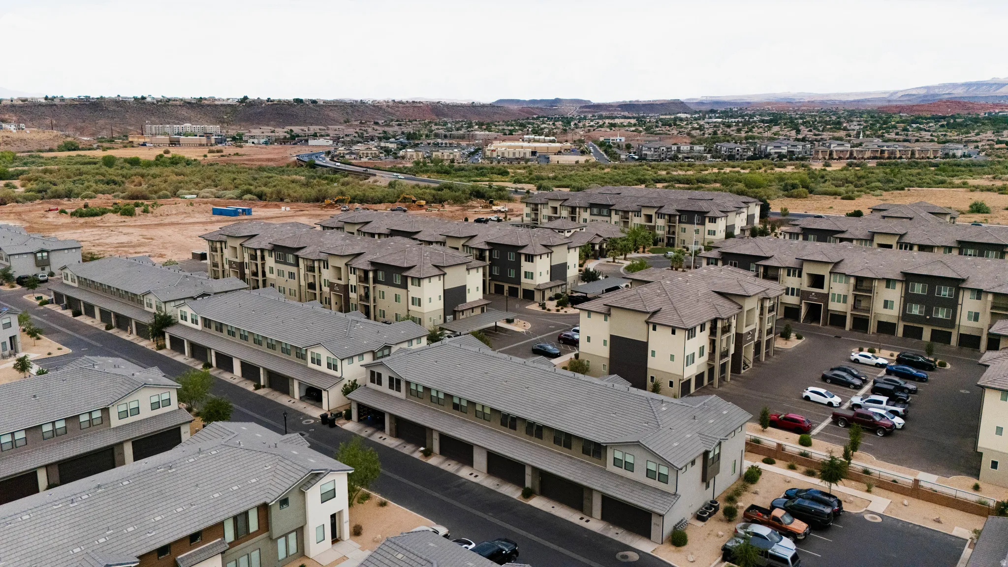 Multi-story residential buildings featuring contemporary architectural design elements, neutral-toned stucco and siding exteriors, private balconies, and dedicated surface parking