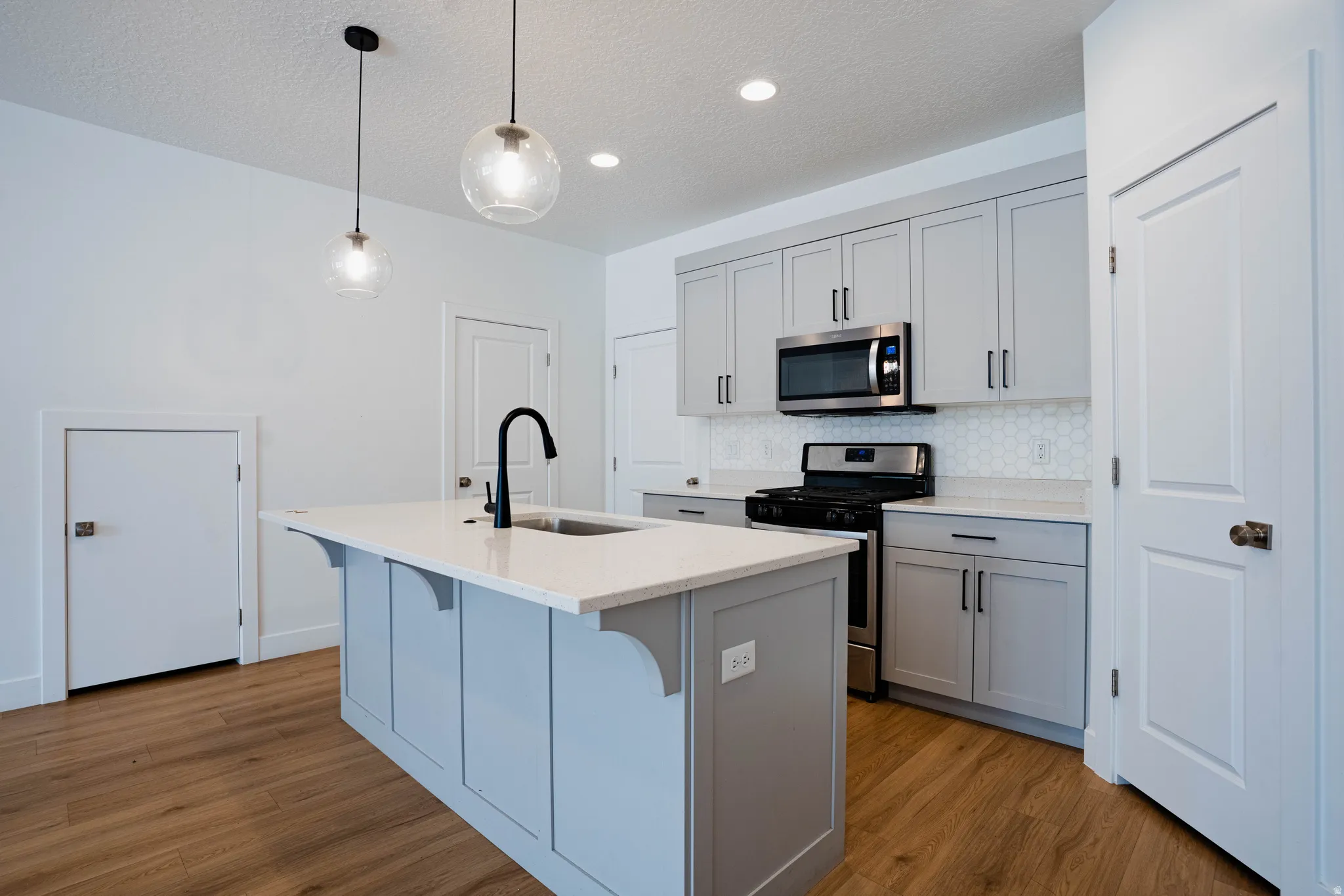 Modern kitchen featuring a light gray island with a white countertop and built-in sink