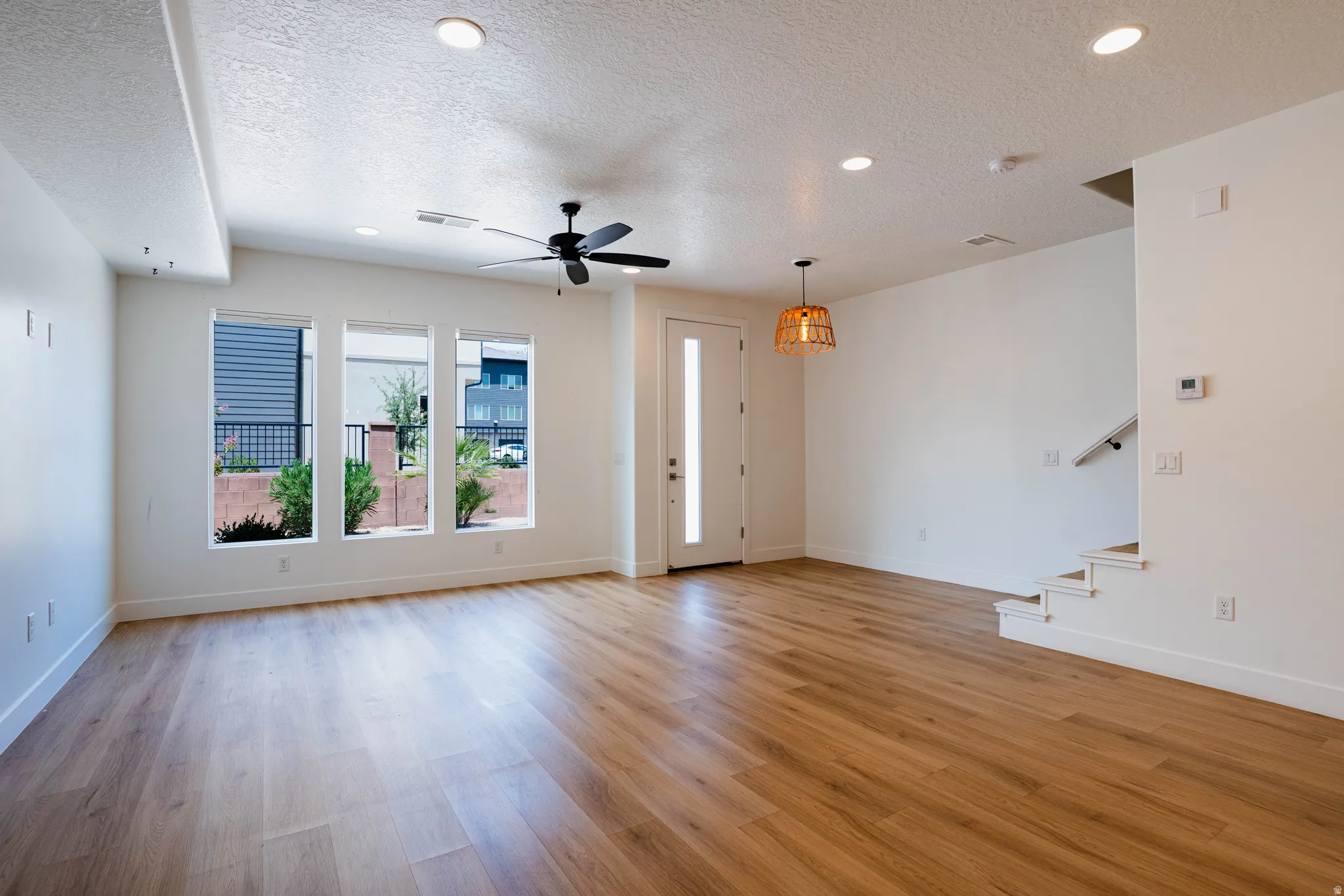 Open-concept living space with wood-finish flooring, recessed lighting, and a modern ceiling fan