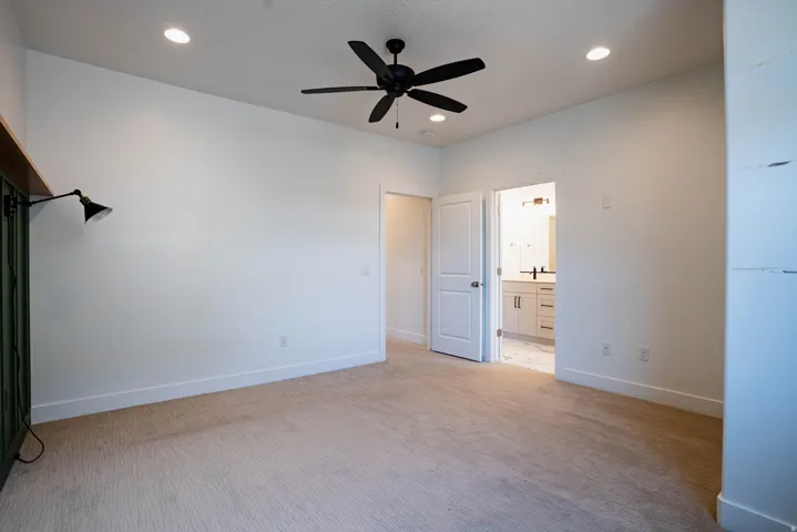 Spacious room featuring neutral carpeting, a contemporary black ceiling fan, and recessed lighting