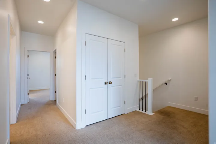 Hallway with light beige carpet flooring, recessed lighting, white walls, and white baseboards