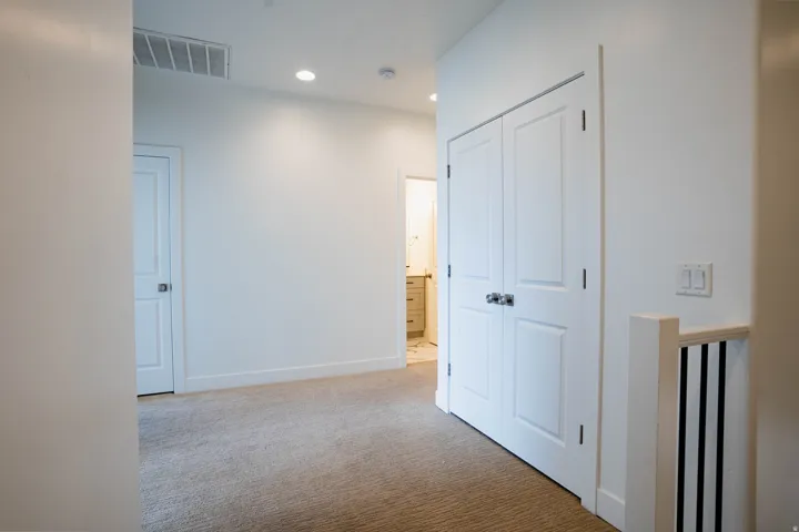 Carpeted hallway with white walls and trim