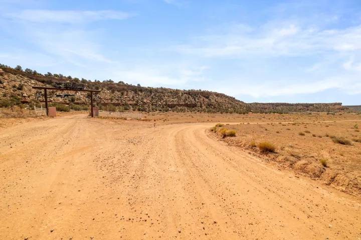 Expansive natural landscape featuring a winding dirt road and a custom entry gate