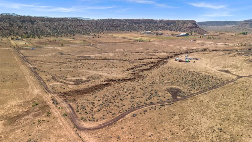 Expansive undeveloped land featuring natural desert vegetation, defined dirt tracks, and scattered structures