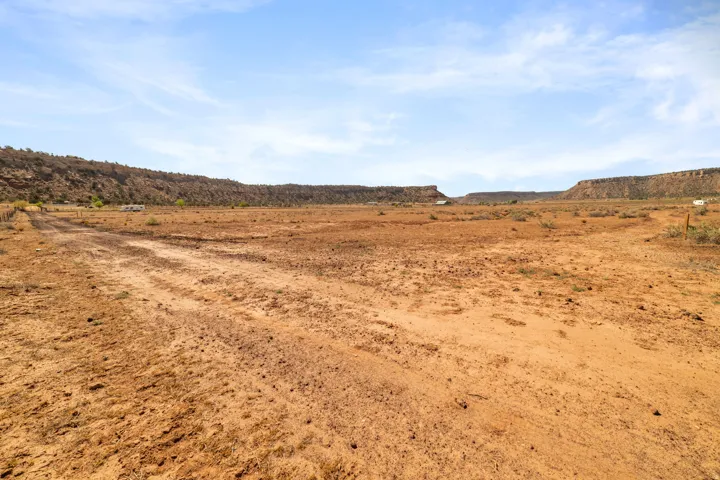 Expansive natural terrain featuring a dirt pathway and distant mesa formations